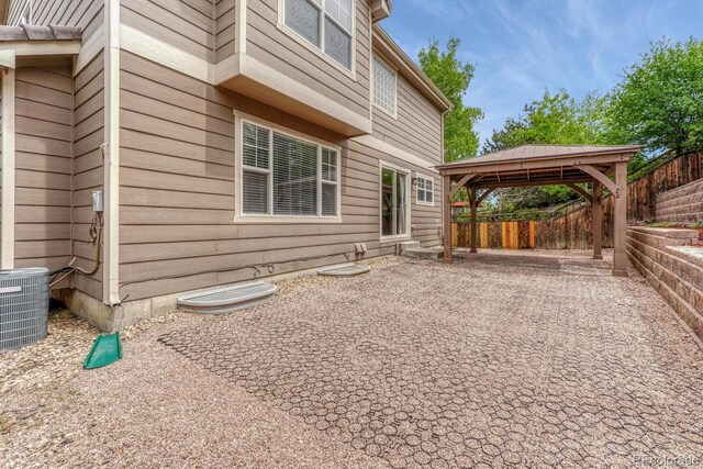 back of property featuring a gazebo, cooling unit, fence, a carport, and a patio area