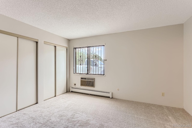 unfurnished bedroom featuring light colored carpet, a textured ceiling, and baseboard heating