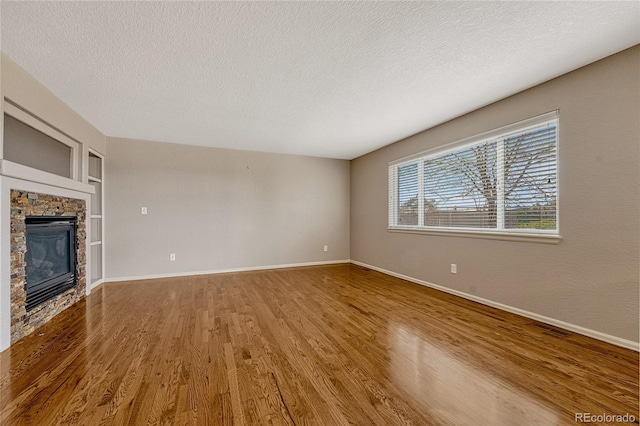 unfurnished living room with a fireplace, a textured ceiling, and hardwood / wood-style flooring