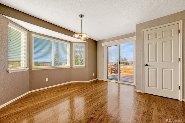 spare room with hardwood / wood-style floors, a textured ceiling, and a notable chandelier