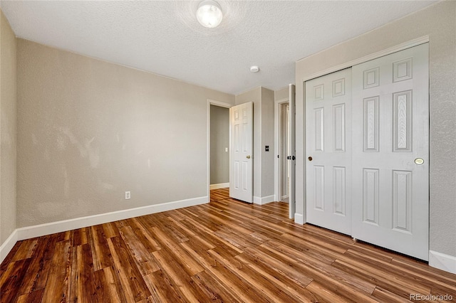 unfurnished bedroom with a textured ceiling, hardwood / wood-style flooring, and a closet