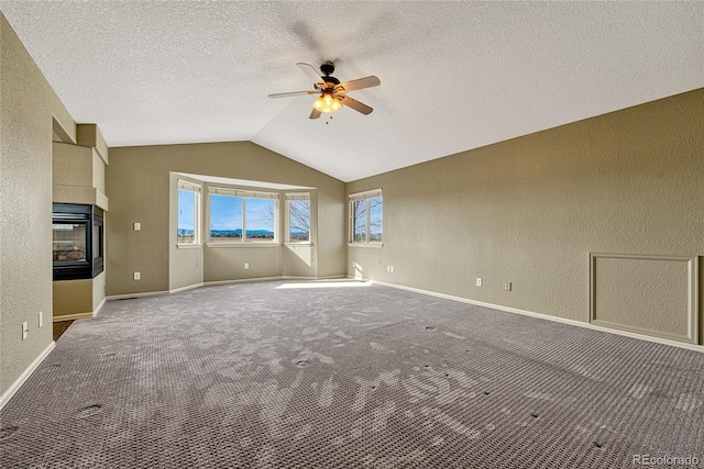 unfurnished living room with a textured ceiling, ceiling fan, carpet, and vaulted ceiling