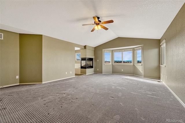 unfurnished living room featuring carpet, a textured ceiling, ceiling fan, a multi sided fireplace, and lofted ceiling