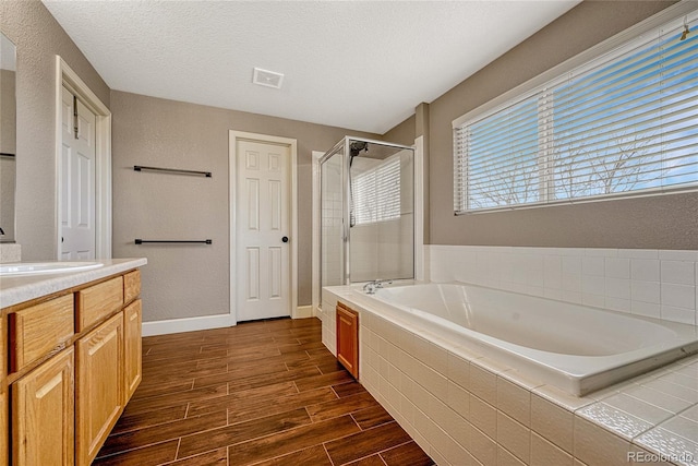 bathroom with a textured ceiling, vanity, and independent shower and bath