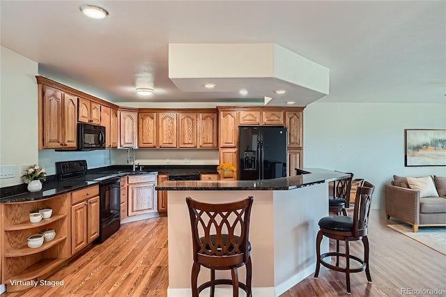 9335 E Center Ave Unit 7B, Denver, CO 80247 - kitchen with black appliances, a sink, light wood-style flooring, a kitchen breakfast bar, and recessed lighting