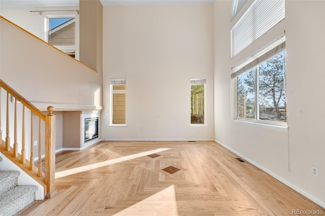 274 W Willowick Cir, Highlands Ranch, CO 80129 - unfurnished living room with a towering ceiling, stairs, and a glass covered fireplace