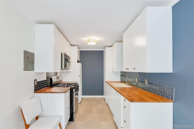 kitchen featuring white cabinetry, sink, stainless steel appliances, and wood counters