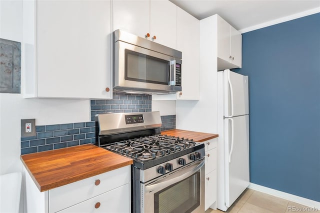 kitchen with wood counters, backsplash, white cabinetry, stainless steel appliances, and baseboards