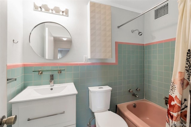 bathroom with visible vents, toilet, tile walls, shower / bath combination with curtain, and vanity