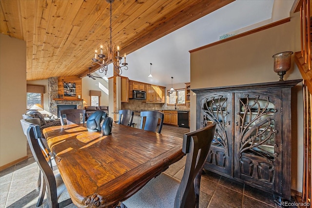 dining area featuring a notable chandelier, wood ceiling, vaulted ceiling, a stone fireplace, and baseboards