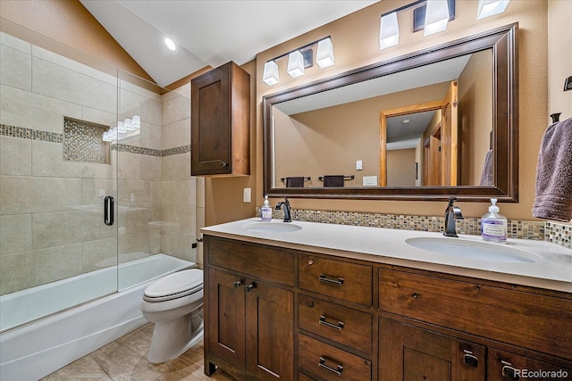 bathroom featuring toilet, double vanity, vaulted ceiling, and a sink