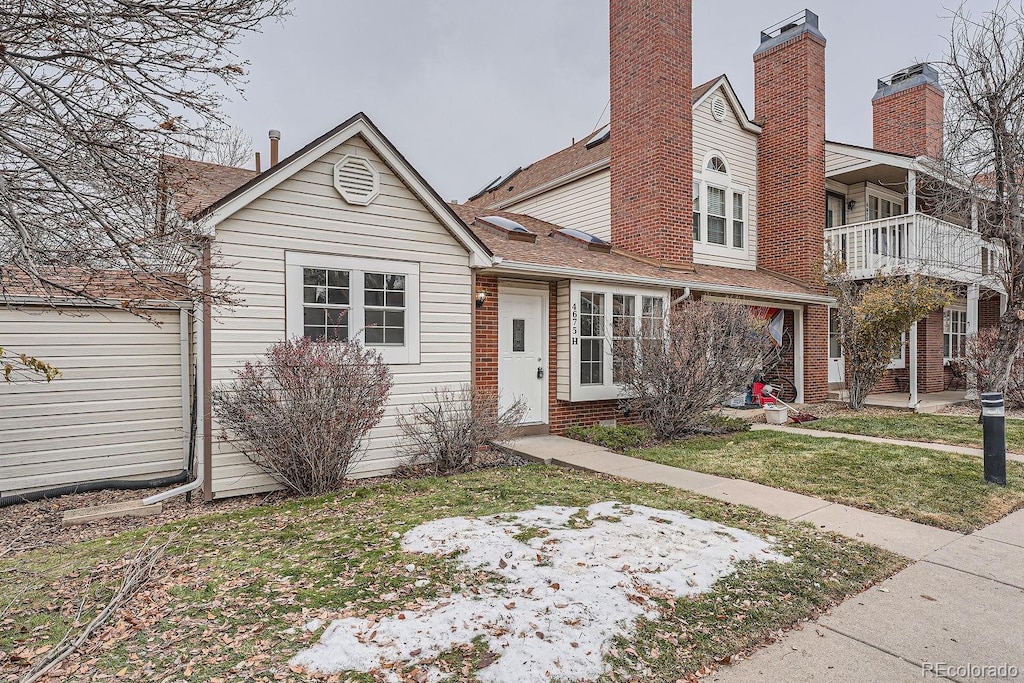 view of front of house with a balcony and a front lawn