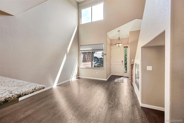 foyer featuring dark wood-style flooring, a high ceiling, and baseboards