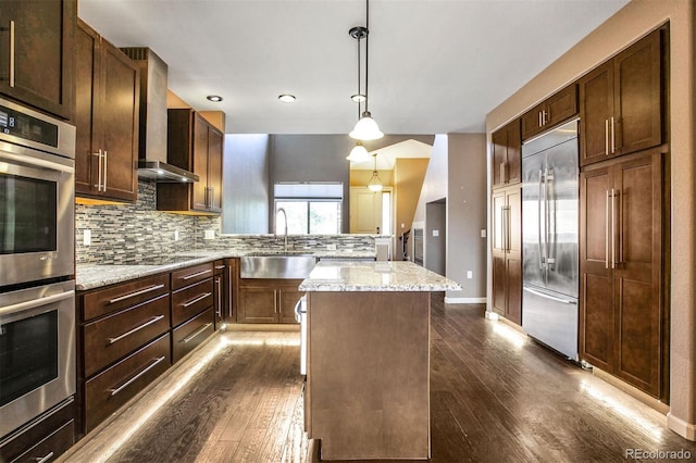 kitchen with dark wood-style flooring, a sink, stainless steel appliances, decorative backsplash, and a kitchen island