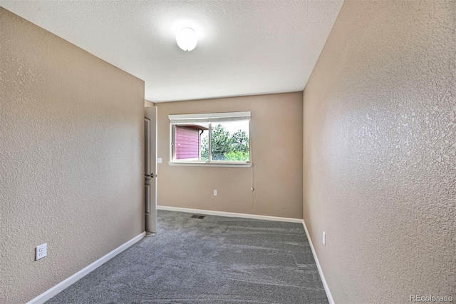 carpeted empty room featuring baseboards and a textured wall