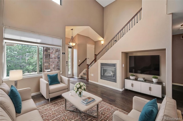 living room featuring stairway, baseboards, wood finished floors, and a towering ceiling