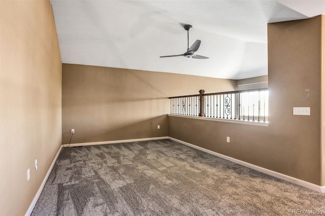 carpeted spare room featuring vaulted ceiling, baseboards, and a ceiling fan