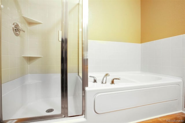 bathroom featuring a stall shower and a bath