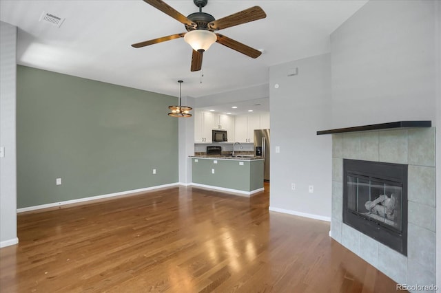 16062 E Geddes Dr Unit 150, Aurora, CO 80016 - unfurnished living room featuring a sink, baseboards, a tile fireplace, and wood finished floors
