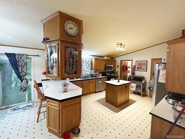 1130 Denver Ave, Saguache, CO 81149 - kitchen featuring stainless steel appliances, a kitchen island, a textured ceiling, a peninsula, and brown cabinetry