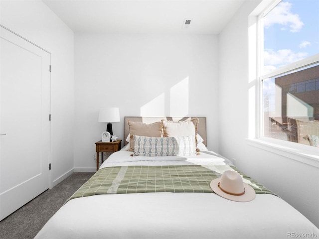 carpeted bedroom featuring multiple windows and baseboards
