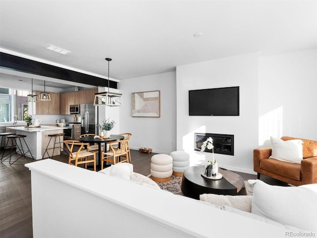 living area with baseboards, dark wood-style floors, and a glass covered fireplace