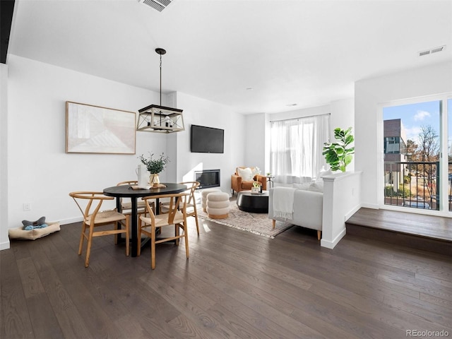 dining room with dark wood-style floors, a glass covered fireplace, and baseboards