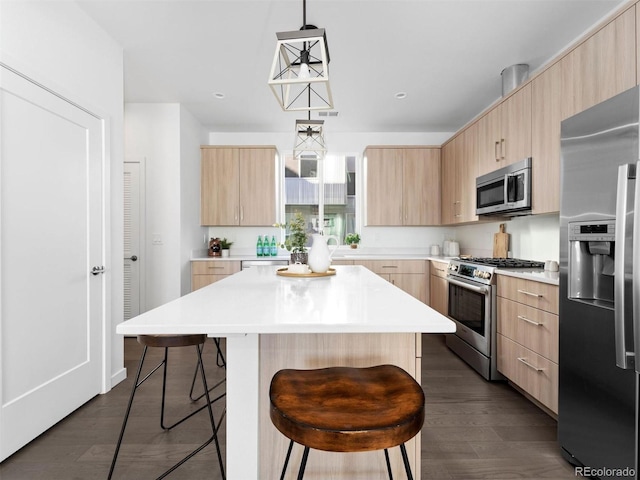 kitchen featuring stainless steel appliances, light brown cabinets, a breakfast bar, and modern cabinets