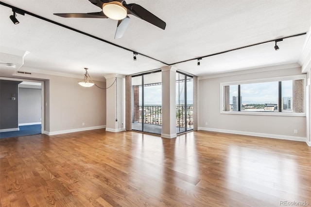 empty room with hardwood / wood-style floors, crown molding, and a healthy amount of sunlight