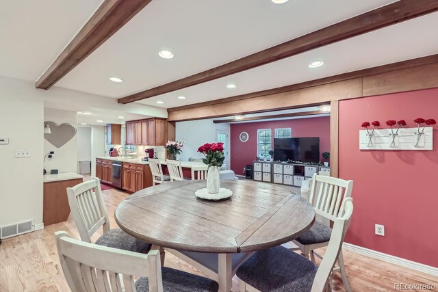 dining room with beam ceiling, light hardwood / wood-style floors, and sink