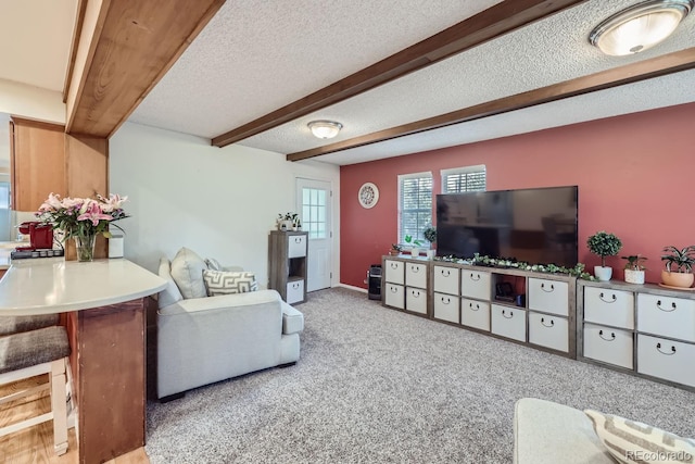 carpeted living room featuring a textured ceiling and beam ceiling