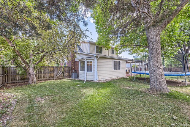 view of yard featuring a trampoline and central AC