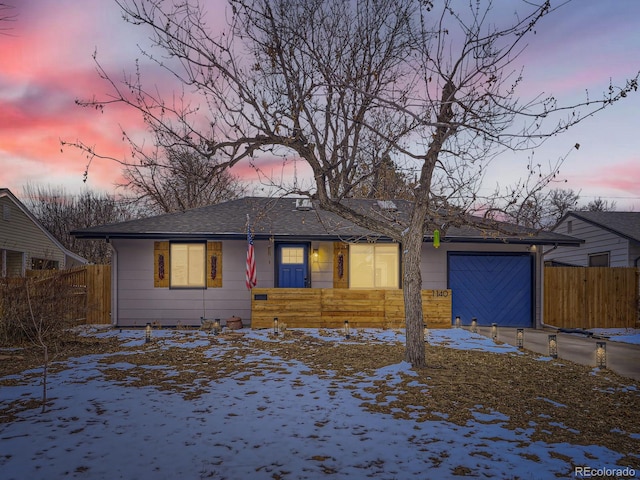 view of front facade with driveway, an attached garage, and fence