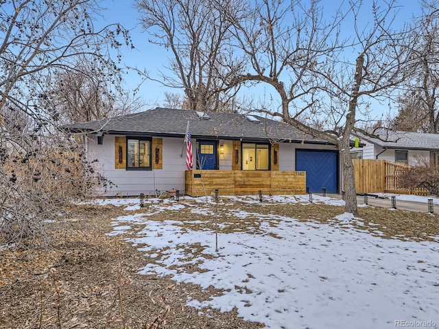 ranch-style home with fence, an attached garage, and a shingled roof