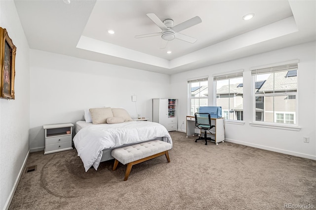 carpeted bedroom featuring a raised ceiling and ceiling fan