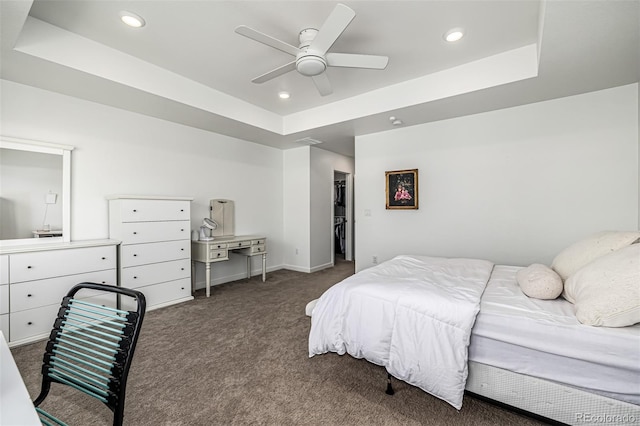 bedroom featuring dark colored carpet, ceiling fan, and a tray ceiling