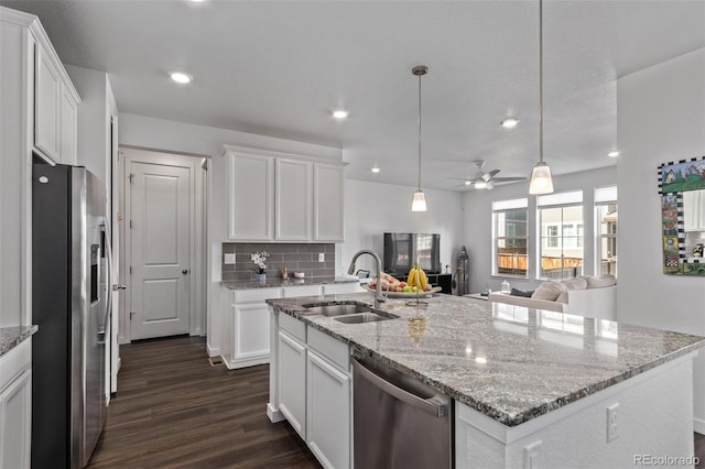 kitchen with white cabinets, stainless steel appliances, a sink, and open floor plan