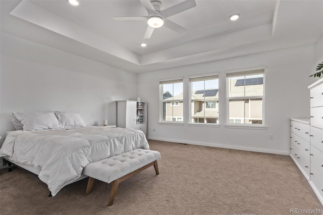 bedroom featuring baseboards, a raised ceiling, and light colored carpet