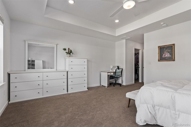 carpeted bedroom featuring baseboards, a raised ceiling, ceiling fan, a walk in closet, and recessed lighting