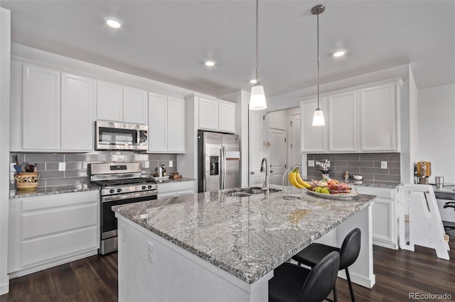 kitchen with light stone countertops, appliances with stainless steel finishes, dark wood-style flooring, and a sink