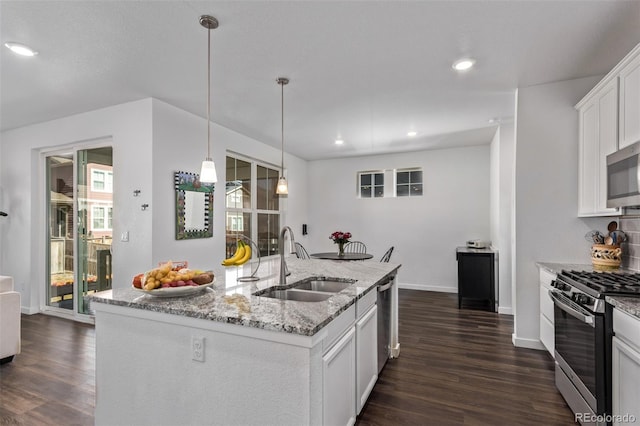 kitchen featuring appliances with stainless steel finishes, dark wood-type flooring, white cabinets, a sink, and light stone countertops