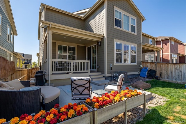 rear view of property featuring a fenced backyard, a porch, an outdoor hangout area, and a patio