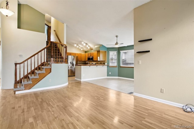 17943 E Bates Ave, Aurora, CO 80013 - unfurnished living room with a ceiling fan, stairway, light wood-style flooring, baseboards, and vaulted ceiling