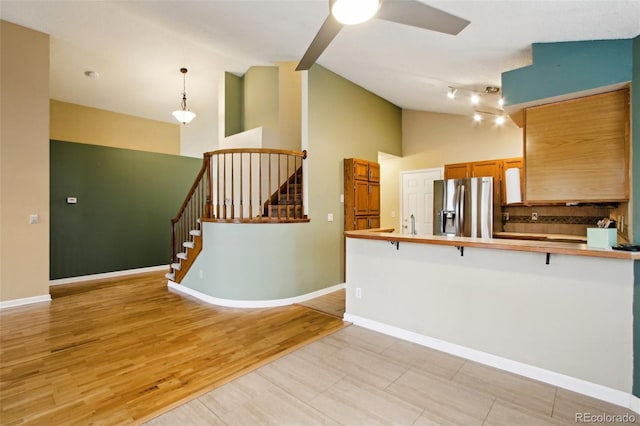 17943 E Bates Ave, Aurora, CO 80013 - kitchen featuring stainless steel fridge, a breakfast bar, brown cabinets, a peninsula, and ceiling fan