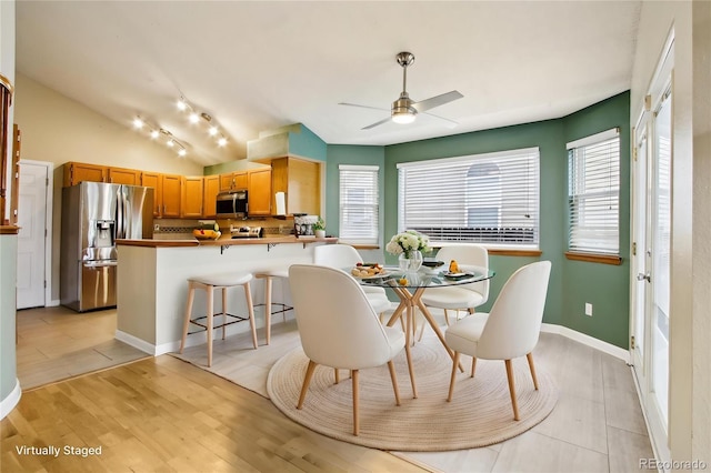 17943 E Bates Ave, Aurora, CO 80013 - dining space with vaulted ceiling, ceiling fan, baseboards, and light wood-style flooring
