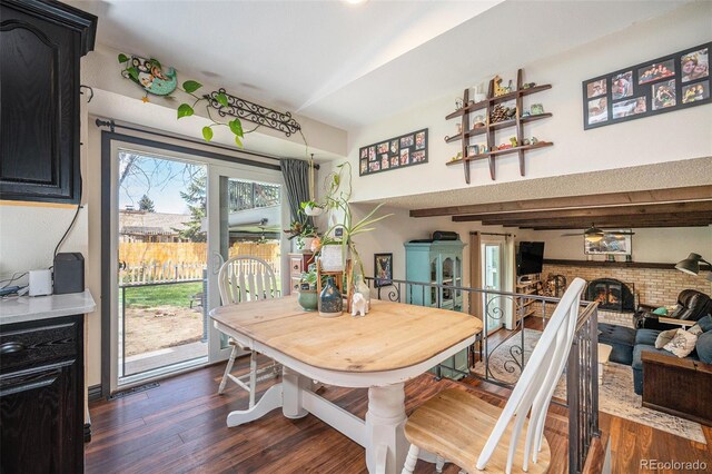 dining room featuring ceiling fan, dark wood-style floors, and a fireplace