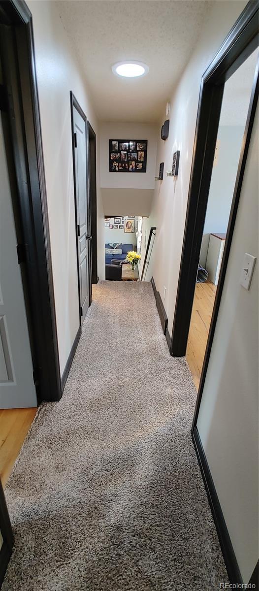 corridor featuring baseboards, an upstairs landing, and light carpet