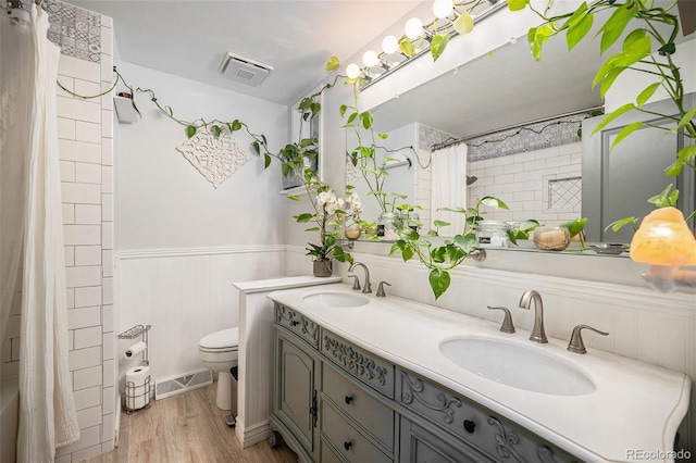 bathroom featuring visible vents, a sink, wainscoting, and toilet