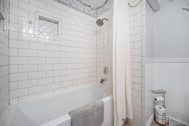 full bath with a wainscoted wall and shower / bath combo