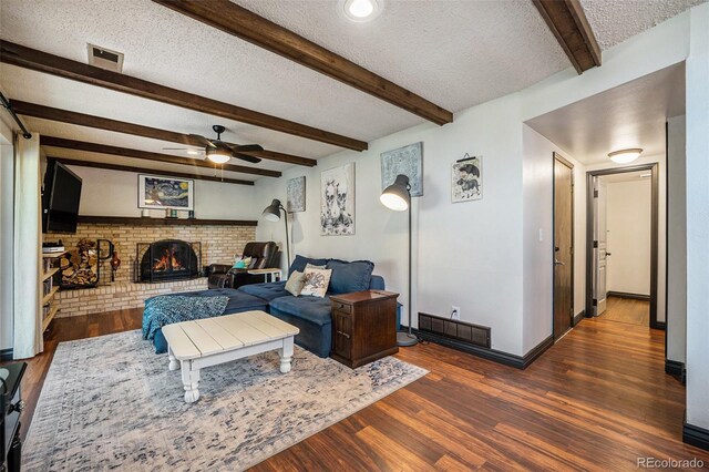living area with wood finished floors, ceiling fan, a textured ceiling, and visible vents